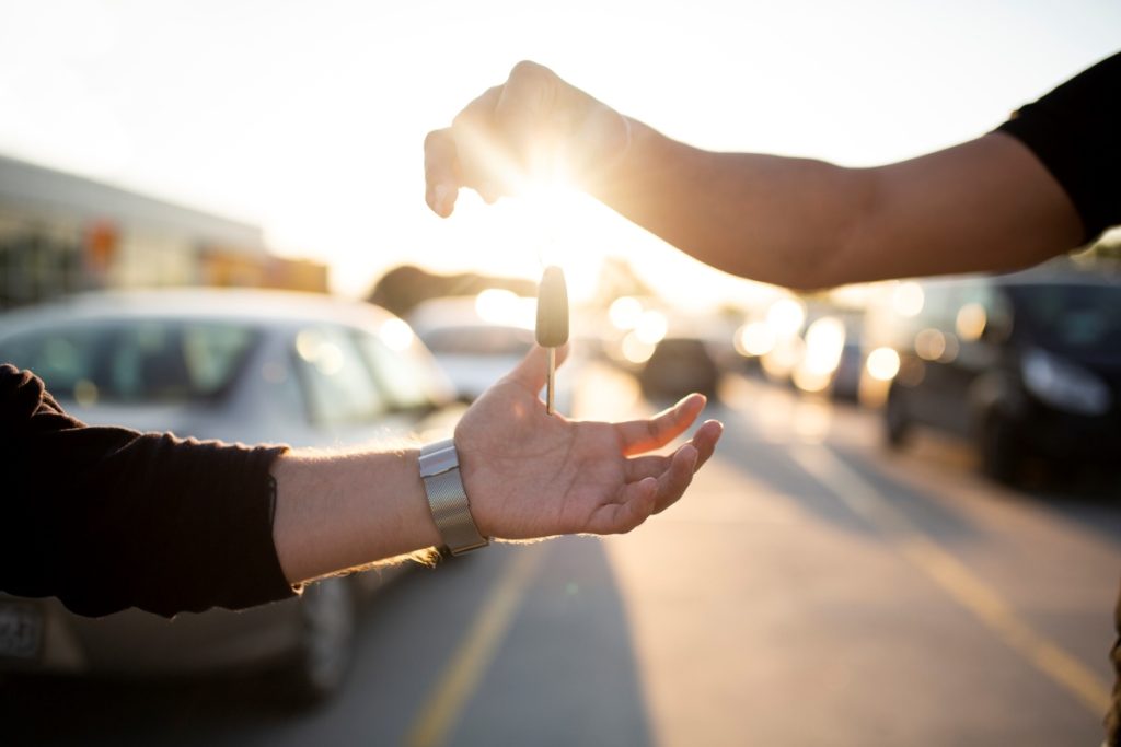 A car rental agent hands over car keys to a customer.